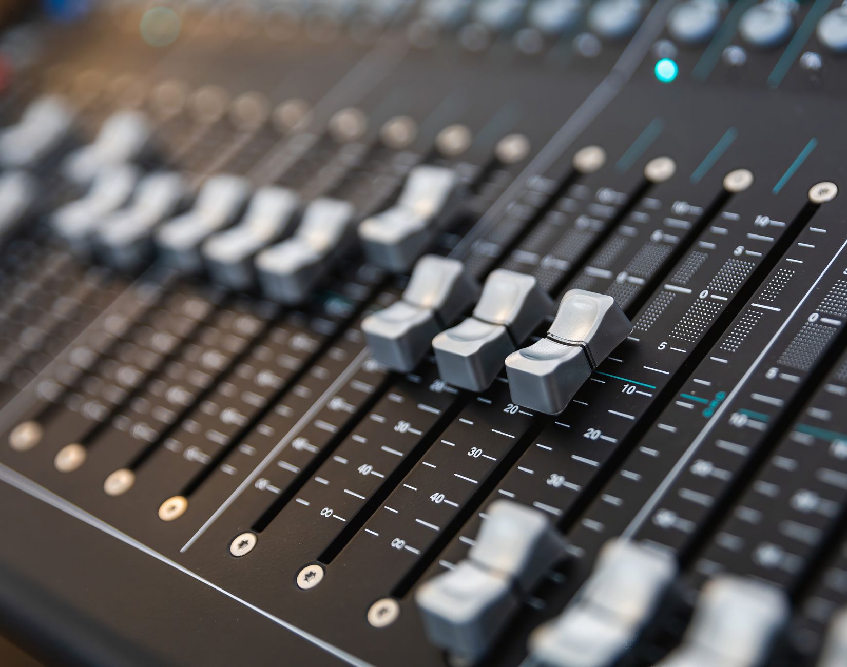 薄暗い会場でPA音響機器のフェーダーとつまみを並べた様子でデジタルとアナログの違いを表現